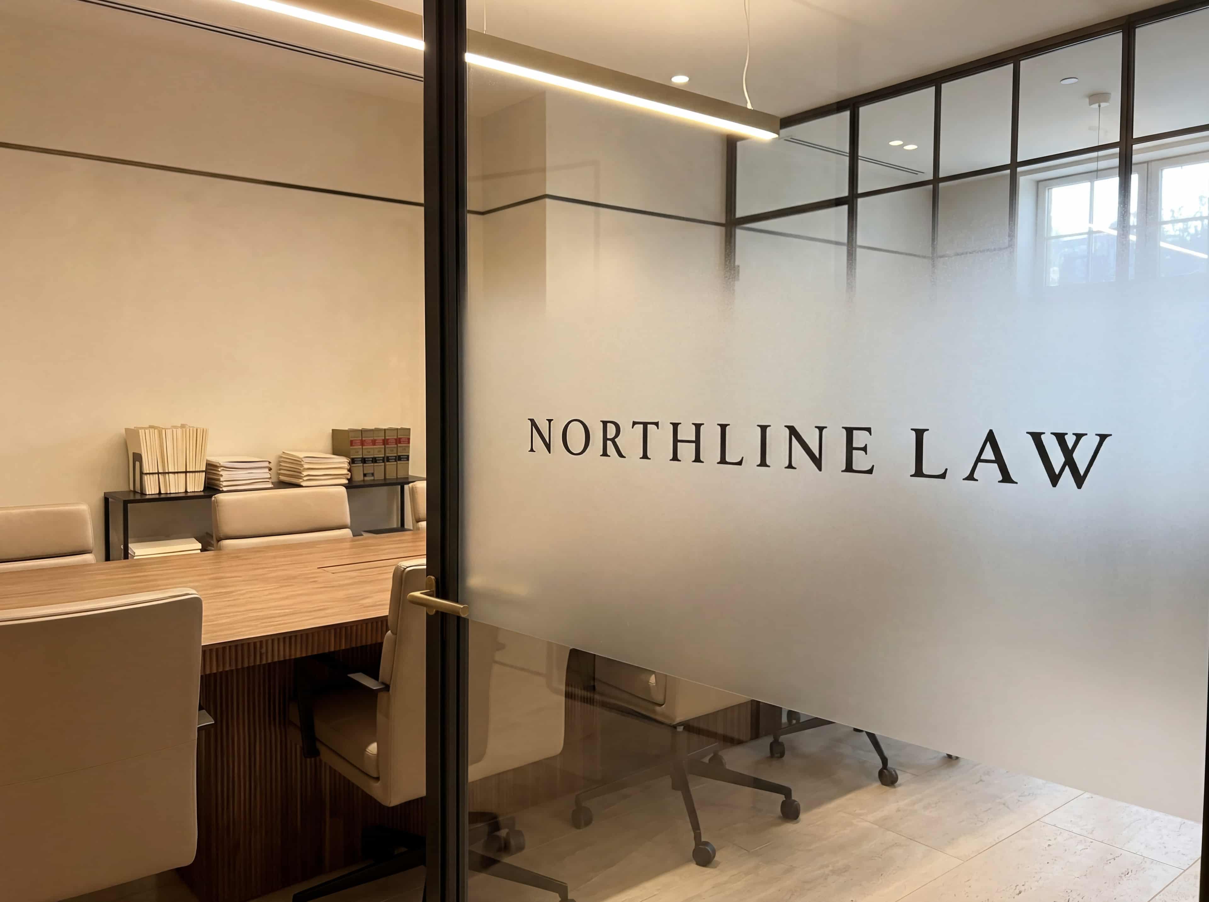 Frosted glass meeting room partition with a subtle Northline Law logo etched into it